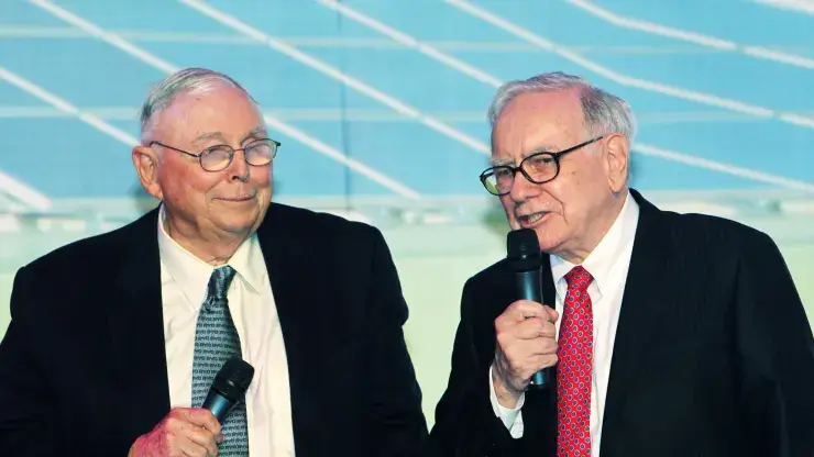 Old Charlie Munger and Warren Buffett addressing people on a Mic